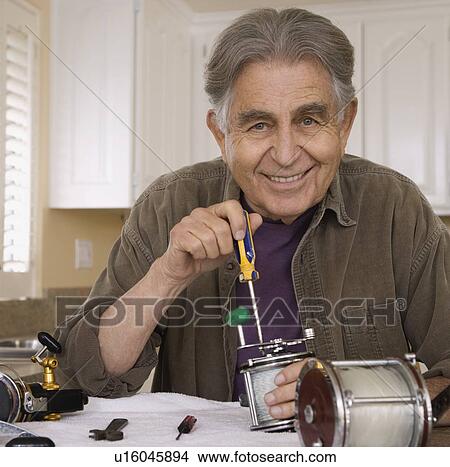 Picture - Senior man fixing fishing reel. Fotosearch