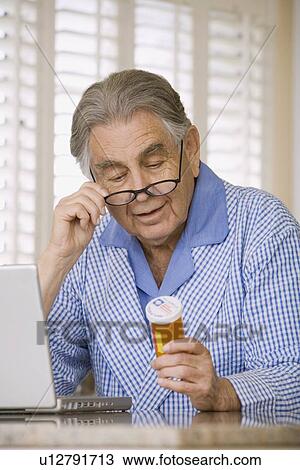 Senior man reading medication bottle View Large Photo Image Stock Image - Senior man reading medication bottle. Fotosearch