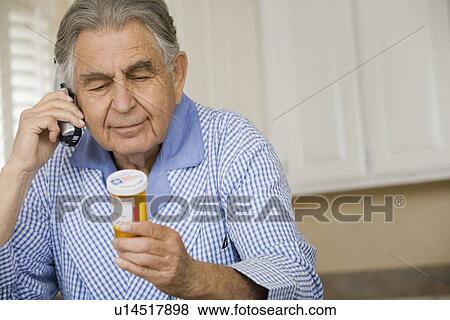 Stock Photo - Senior man reading medication bottle. Fotosearch