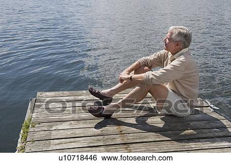 Stock Photograph - Senior man sitting on dock. Fotosearch