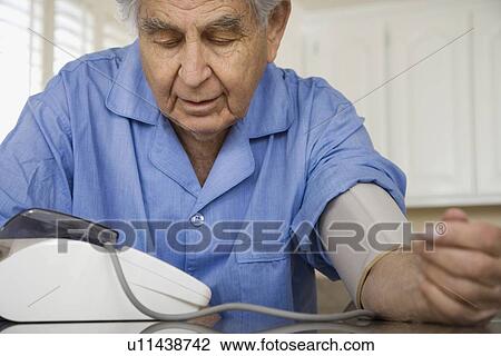 Stock Image - Senior man taking own blood pressure. Fotosearch