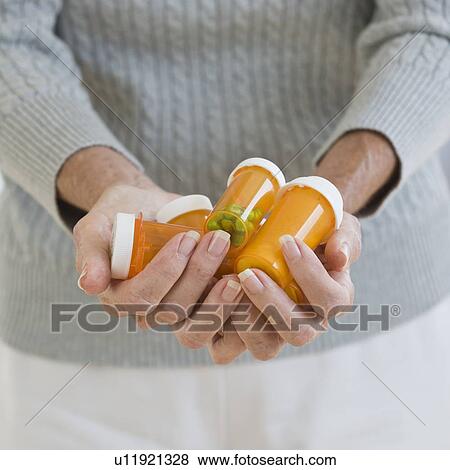 Stock Photo - Senior woman holding prescription bottles. Fotosearch
