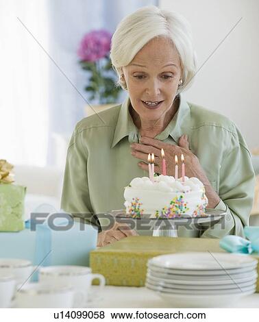 Stock Photo - Senior woman looking at birthday cake. Fotosearch