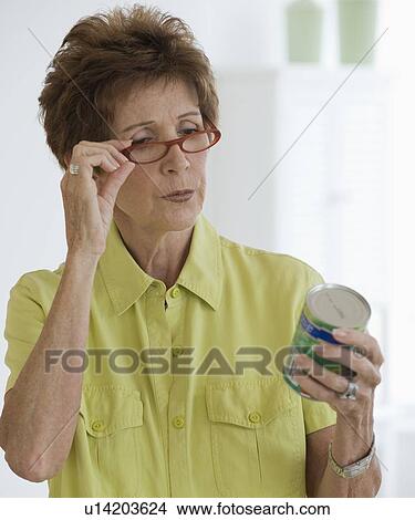 Senior woman reading label on food can View Large Photo Image Picture - Senior woman reading label on food can. Fotosearch