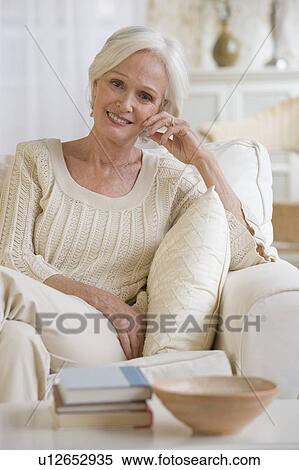 Stock Photography - Senior woman relaxing in livingroom. Fotosearch