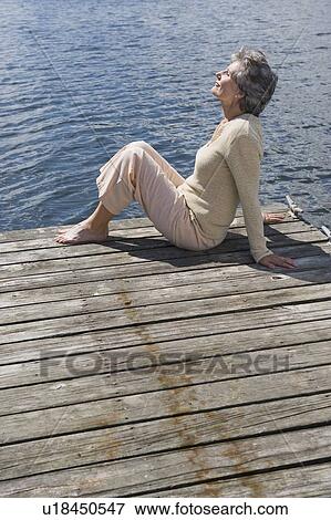 Senior woman sitting on dock View Large Photo Image Stock Photo - Senior woman sitting on dock. Fotosearch