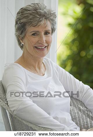 Stock Image - Senior woman sitting on porch. Fotosearch