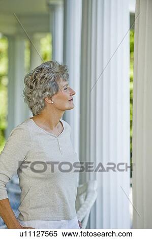 Stock Photography - Senior woman standing on porch. Fotosearch