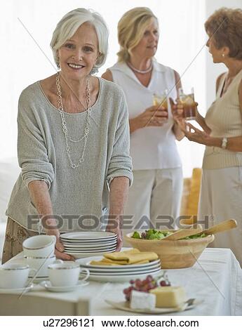 Stock Image - Senior women socializing at luncheon. Fotosearch