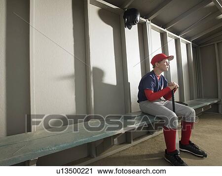 Stock Image - Serious baseball player sitting in dugout. Fotosearch