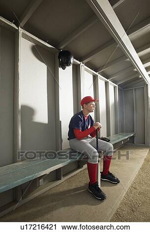 Stock Image - Serious baseball player sitting in dugout. Fotosearch