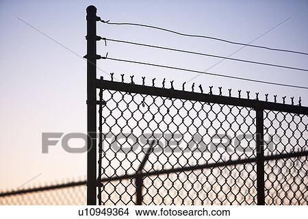 Silhouette of barbed wire and chain-link fence View Large Photo Image Picture - Silhouette of barbed wire and chain-link fence. Fotosearch
