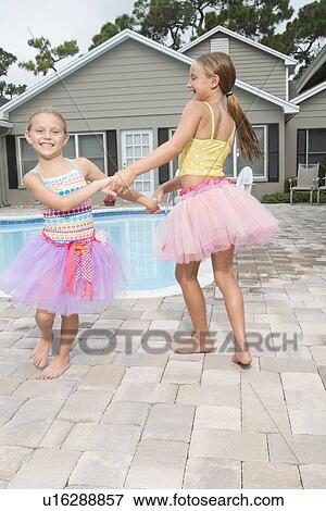 Stock Photo - Sisters playing by swimming pool. Fotosearch