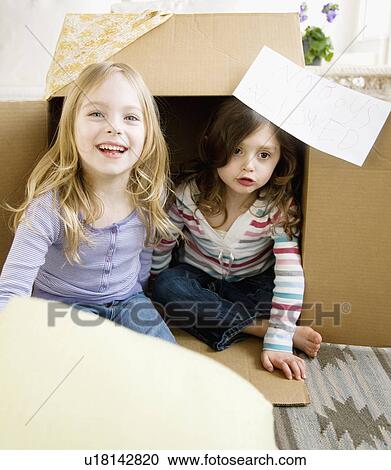 Stock Image - Sisters playing in cardboard box. Fotosearch