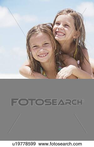 Stock Photo - Sisters playing in ocean. Fotosearch