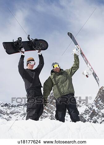 Picture - Snowboarders holding snowboards over heads. Fotosearch