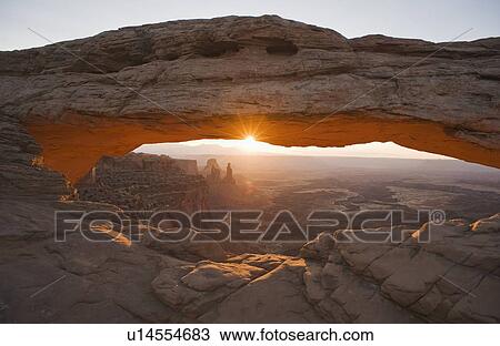 Stock Image - Sun shining behind Mesa Arch, Canyonlands National Park, Utah. Fotosearch