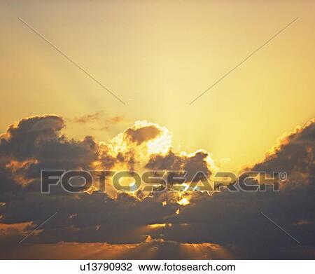 Stock Image - Sun shining through clouds. Fotosearch