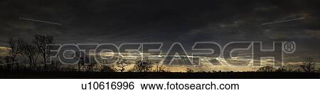 Stock Photograph - Sunbeams shining from clouds over African landscape. Fotosearch