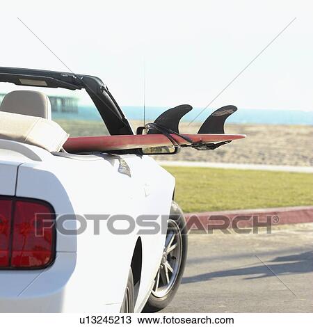 Stock Image - Surfboard in convertible car. Fotosearch