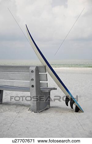 Stock Image - Surfboard leaning against bench. Fotosearch