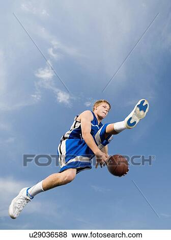 Stock Photo - Teenage basketball player in mid-air with basketball. Fotosearch