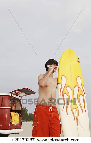 Teenage boy holding surfboard on beach View Large Photo Image Stock Photo - Teenage boy holding surfboard on beach. Fotosearch