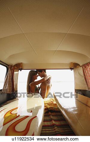 Picture - Teenage couple hugging at back of van. Fotosearch