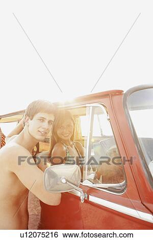 Stock Photograph - Teenage couple relaxing in van on beach. Fotosearch