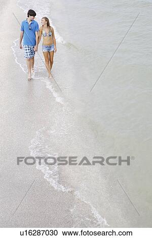 Teenage couple walking in ocean View Large Photo Image Stock Image - Teenage couple walking in ocean. Fotosearch