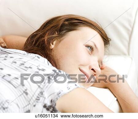 Picture - Teenage girl daydreaming on sofa. Fotosearch