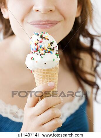 Stock Image - Teenage girl eating ice cream cone. Fotosearch