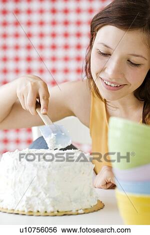 Stock Photograph - Teenage girl frosting cake. Fotosearch