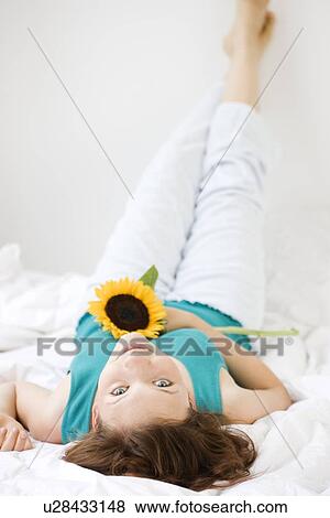 Stock Photo - Teenage girl holding flower in bed. Fotosearch