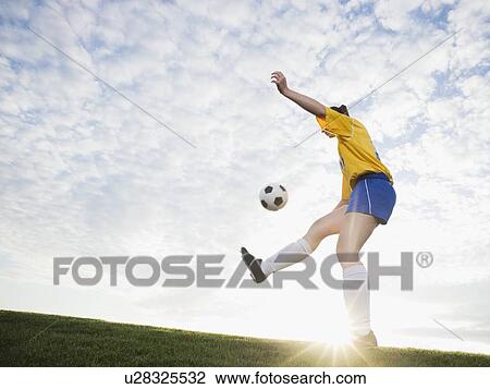 Stock Image - Teenage girl kicking soccer ball. Fotosearch