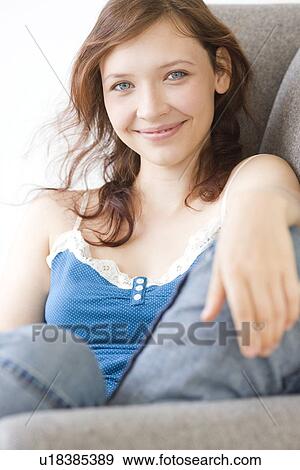 Stock Photo - Teenage girl relaxing on arm chair. Fotosearch