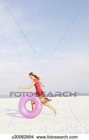 Teenage girl rolling inflatable ring on beach View Large Photo Image Picture - Teenage girl rolling inflatable ring on beach. Fotosearch