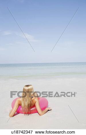 Teenage girl sitting in inflatable ring in shallow ocean View Large Photo Image Stock Photo - Teenage girl sitting in inflatable ring in shallow ocean. Fotosearch