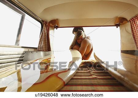Stock Photo - Teenage surfers hugging by van. Fotosearch