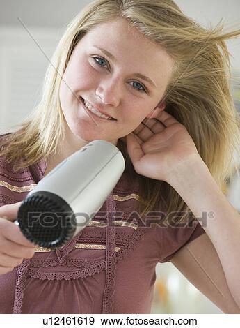 Stock Photo - Teenaged girl blow drying hair. Fotosearch
