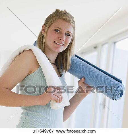 Stock Photo - Teenaged girl holding rolled yoga mat. Fotosearch