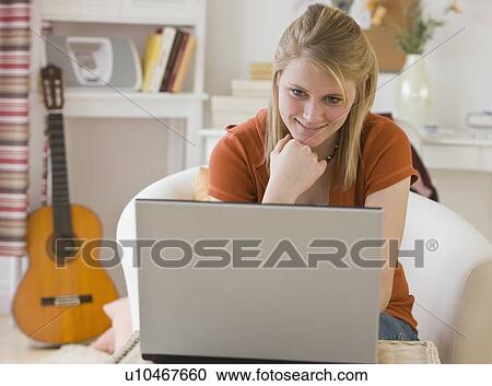 Stock Image - Teenaged girl looking at laptop. Fotosearch