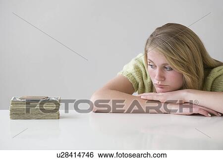 Stock Photograph - Teenaged girl looking at stack of money. Fotosearch