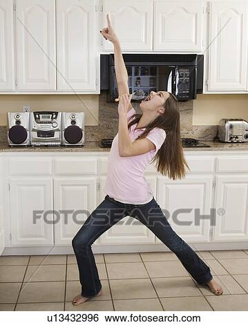 Teenaged girl singing in kitchen View Large Photo Image Stock Photograph - Teenaged girl singing in kitchen. Fotosearch