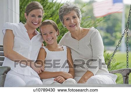 Stock Image - Three generations of women sitting on porch. Fotosearch