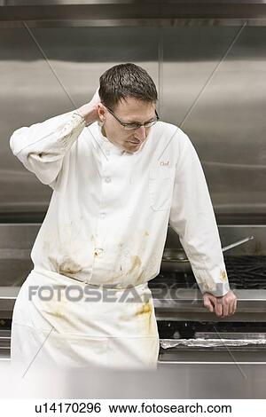 Stock Photograph - Tired chef leaning against stove. Fotosearch