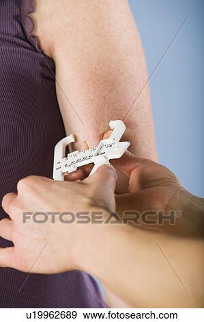 Stock Photo - Trainer measuring body fat percentage. Fotosearch