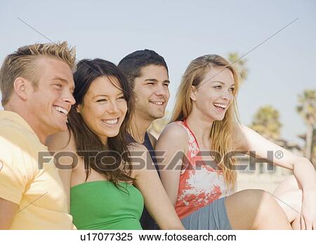 Stock Photography - Two couple sitting on beach. Fotosearch