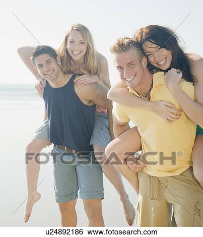 Two men giving piggy back rides to girlfriends View Large Photo Image Stock Photograph - Two men giving piggy back rides to girlfriends. Fotosearch