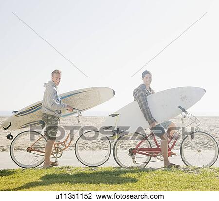 Two men with surfboards on bicycles View Large Photo Image Stock Image - Two men with surfboards on bicycles. Fotosearch